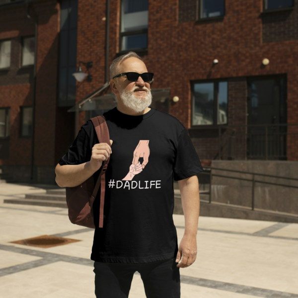 Man wearing an oversized black t-shirt with "#DadLife" and a design of a kid's hand shaking with his dad's hand by Attire Dot