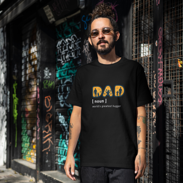 Man wearing an oversized black t-shirt with the text "Dad [noun] World's Greatest Hugger" and a silhouette design of a dad with kids, by Attire Dot